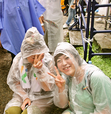 雨具を着てピースする女性